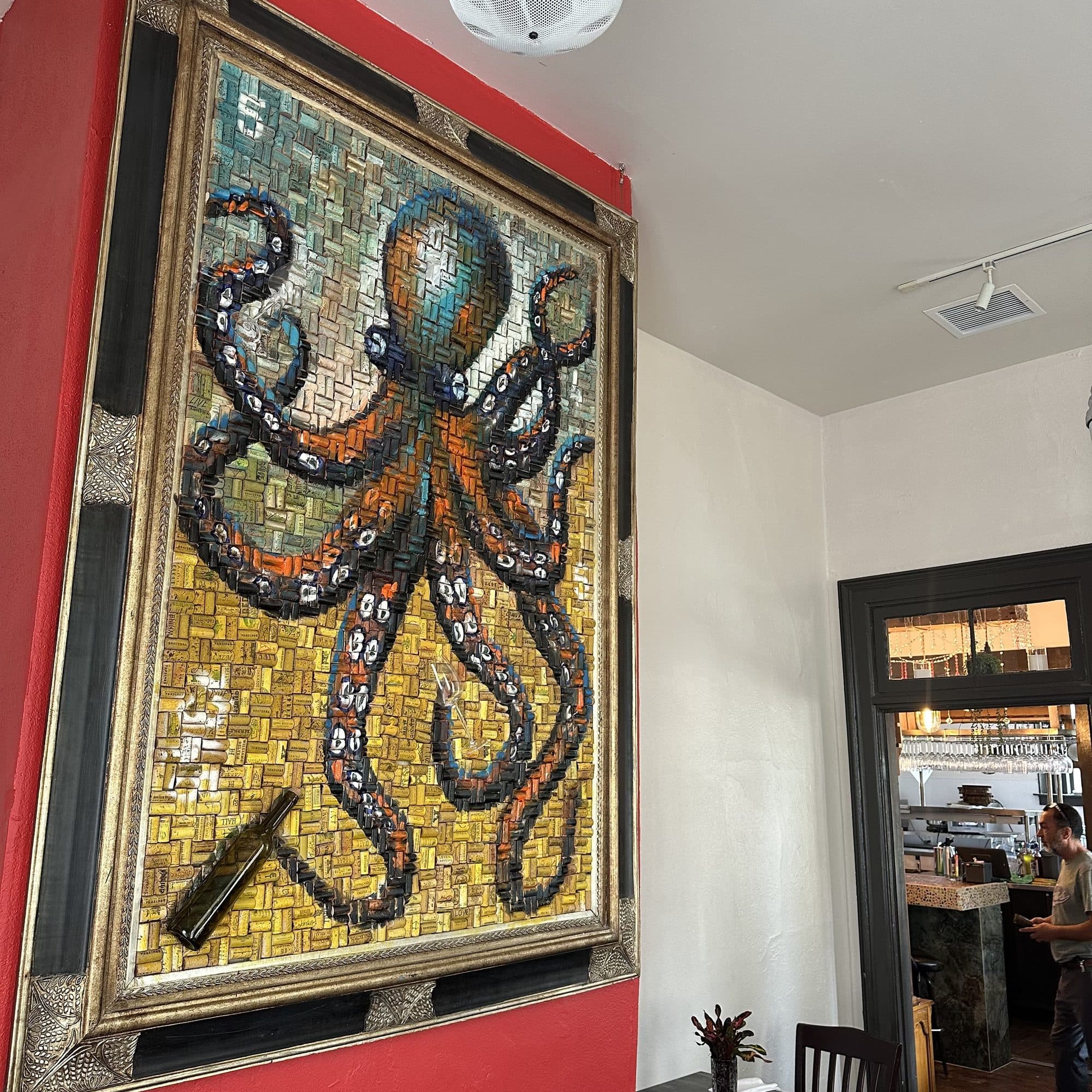 Gold-framed mosaic of an octopus on a red wall